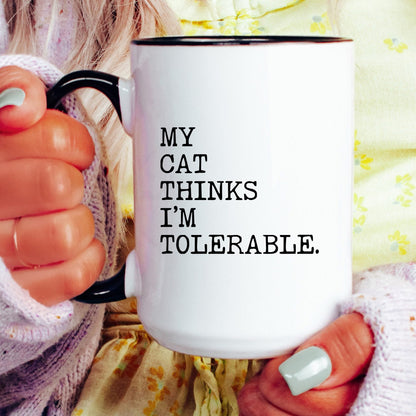 My Cat Thinks I’m Tolerable coffee mug held by a model